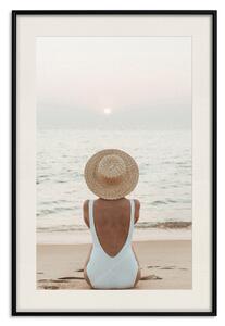Plakát Odpočinek na pláži - žena sedící na písku se západem slunce v pozadí
