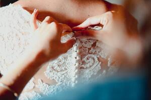 Umělecká fotografie Close-up of a bridesmaid buttoning up, corinafotografia, (40 x 26.7 cm)