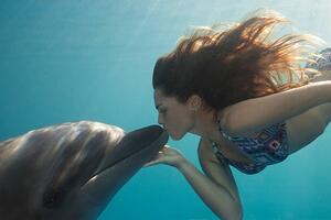 Umělecká fotografie Young Woman Kisses Dolphin Underwater, Sunbeams, Justin Lewis, (40 x 26.7 cm)
