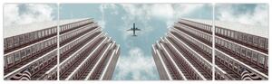 Obraz letadla mezi budovami (170x50 cm)