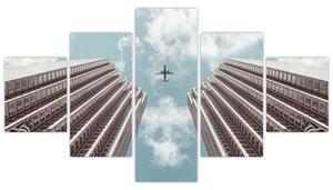 Obraz letadla mezi budovami (125x70 cm)