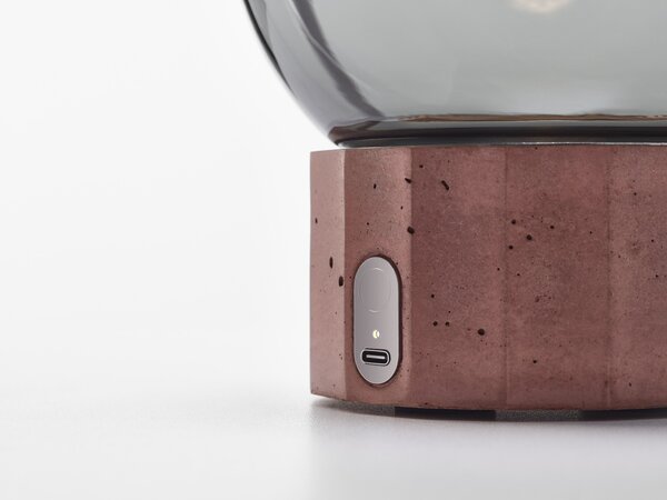 Brokis Designové přenosné svítidlo Sfera Portable PC1273, Ø40 cm, IP44 Povrch Montury: kov - černý matný komaxit (CCS846), Barva skla: šedá kouřová - transparentní sklo (CGC516), Povrchová úprava základny: vysokohodnotný beton - přírodní (CSFB2840)